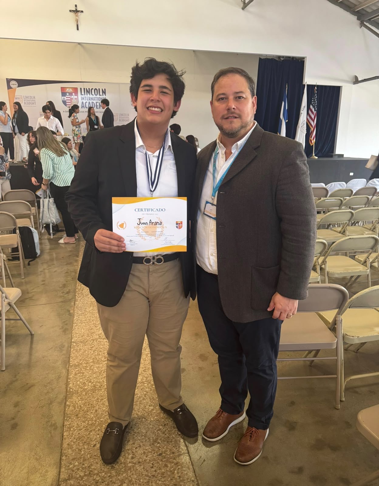 Juan holding an honorable mention certificate and wearing a medal at Lincoln International Academy