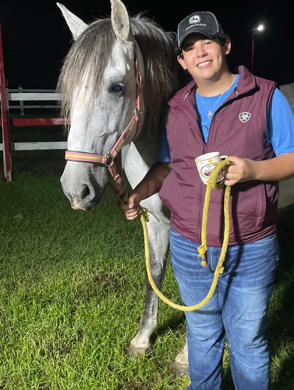 Juan standing beside a gray horse at night